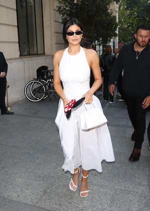 Kylie Jenner wears a white dress with a fitted top and billowy skirt and black sunnies in Paris. 
