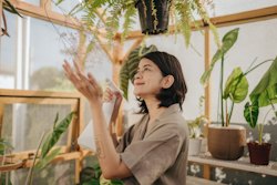 Happy woman working in greenhouse. Your guide to earth signs; earth sign guide.